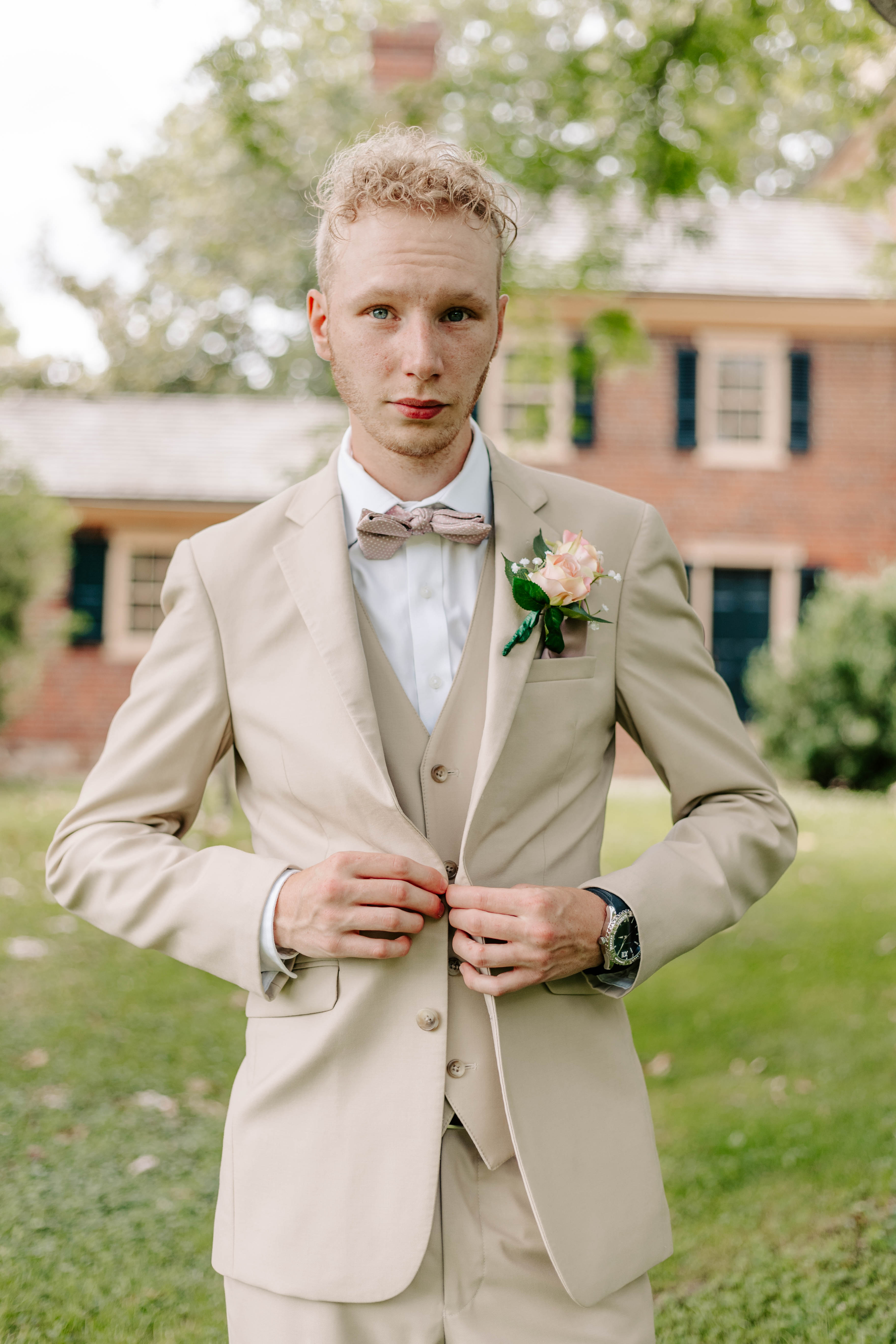 Groom butting tux for getting ready photos at Delaware spring wedding  at Historic Odessa. Delaware modern wedding photographer Alli McGrath photographed this candid moment.